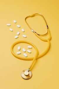 Kaboompics - Yellow Stethoscope and White Pills on Golden Background, Healthcare Concept for Medical Design