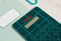 Kaboompics - Teal Calculator on a Mint Label Notebook with Oversized Paper Clip for Math Study