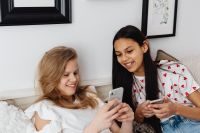 Kaboompics - Two Teenagers Scrolling on Separate Phones While Sitting Side by Side at Home