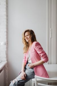 Kaboompics - Side-Glance Portrait of a Blonde Woman in a Pink Blazer Against a Bright Wall