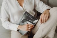 Kaboompics - Woman Seated on a Neutral Sofa with Architecture Book, White Blouse and Beige Trousers
