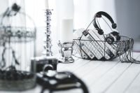 Kaboompics - Wire Basket of Books and Headphones on a White Wood Table