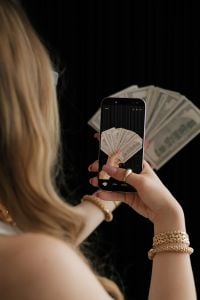 Kaboompics - Woman Taking a Photo of Dollar Bills Growth Manifestation
