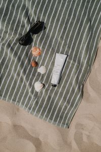 Kaboompics - Striped Beach Towel with Sunglasses, Seashells and Sunscreen