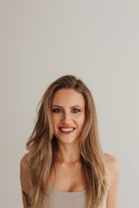 Kaboompics - Close-Up Portrait of Smiling Woman Against a Neutral Wall
