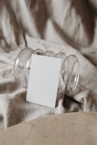 Kaboompics - Portrait Card Mockup Leaning against Stacked Glass Vases