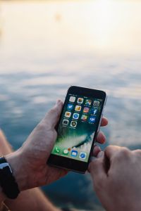 Kaboompics - Vertical Smartphone with App Icons Against a Soft Seaside Horizon