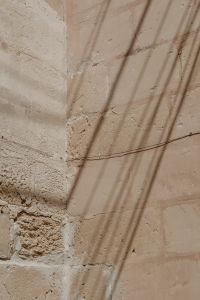 Kaboompics - Weathered Limestone Wall with Sunlit Shadows and Utility Wire