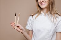 Kaboompics - Female Dentist Holding Bamboo Toothbrushes, Eco-Friendly Dental Care Campaign Portrait