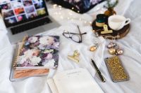 Kaboompics - Overhead Bed Office Flat Lay with Laptop, Floral Journal, Planner, Coffee and Jewelry