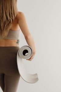 Kaboompics - Woman Holding a Rolled Yoga Mat Seen From Behind