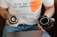 Kaboompics - Hands Holding a DSLR Camera and Lens above a MacBook