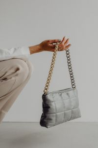 Kaboompics - Woman Seated in Neutral Trousers with Gray Quilted Handbag