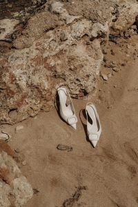 Kaboompics - White Pointed Pumps Resting on a Sunlit Rocky Shore
