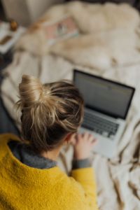 Kaboompics - Top-Down View of Woman Typing on Laptop in Bed, Mustard Knit Sweater