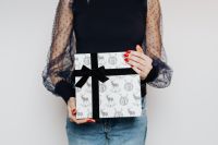 Kaboompics - Close-Up of Deer-Print Gift Box with Black Ribbon in a Woman's Hands
