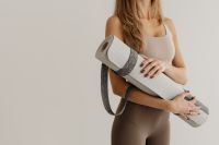 Kaboompics - Woman Holding a Rolled Yoga Mat in Neutral Activewear