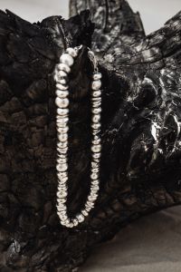 Kaboompics - Close-Up Silver Beaded Necklace on Textured Driftwood