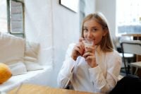 Kaboompics - Close-Up of Woman Sipping Coffee With Smartphone
