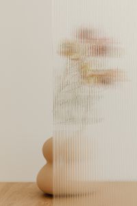 Kaboompics - Soft Focus Pink and Beige Flower Behind Ribbed Glass, Minimal Neutral Still Life