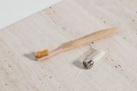 Kaboompics - Bamboo Toothbrush and Refillable Glass Floss Dispenser on Limestone for Zero-Waste Oral Care