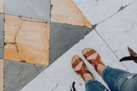Kaboompics - Woman Wearing Brown Leather Sandals and Blue Jeans on Geometric Marble Tiles, Naples Italy Travel Fashion Detail