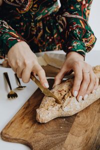 Kaboompics - Hands Cutting Bread on a Wooden Board