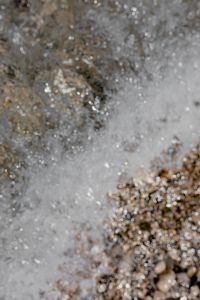 Kaboompics - Foamy Seawater over Wet Pebbles with Bright Sunlit Ripples