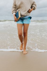 Kaboompics - Barefoot Woman Leaving the Surf with a Book in Hand, Cloudy Beach Reading Lifestyle