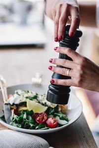 Kaboompics - Close up of female hands flavouring salad in a bowl