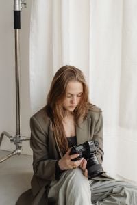 Kaboompics - Seated Young Female Photographer Checking DSLR Camera