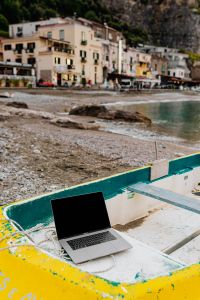 MacBook Laptop on a Yellow Dinghy at a Pebble Beach