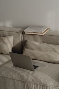 Kaboompics - Open Laptop on a Neutral Sofa with Books on the Backrest, Home Office