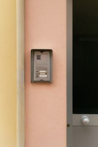 Kaboompics - Modern Doorbell Intercom on Pink Stucco Wall with Yellow Wall Detail