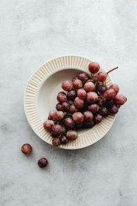 Kaboompics - Ribbed Ceramic Bowl of Red Grapes on a Textured White Surface