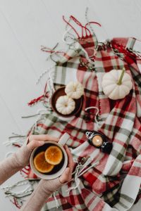 Kaboompics - Hands Holding Orange Tea Above Autumn Blanket Flat Lay