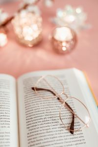 Kaboompics - Rose Gold Glasses on Open Book with Candlelight Bokeh