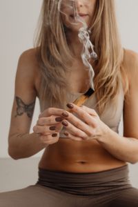 Kaboompics - Woman Holding a Smoking Palo Santo Stick With Rising Smoke