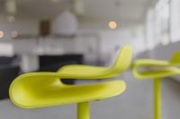Kaboompics - Sculptural Lime Yellow Bar Chair Seat with a Second Stool in a Soft-Focus Showroom