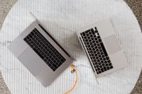 Kaboompics - Overhead Two Silver Laptops on White Marble with Orange Cable