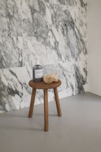 Kaboompics - Wooden Stool with Soap and Loofah Against Arabescato Wall