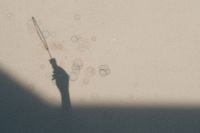 Kaboompics - Shadow of a Hand Holding a Bubble Wand on a Beige Wall