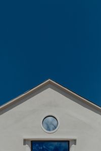 Kaboompics - Minimal White Lisbon Gable with Circular Window Against Deep Blue Sky