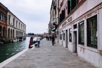 Kaboompics - Pedestrian Strolling Past Shopfronts beside a Murano Canal, Venice Travel Photography