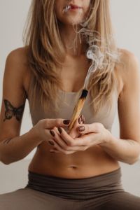 Kaboompics - Seated Woman Holding a Smoking Palo Santo Stick With Both Hands