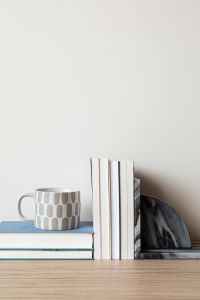 Kaboompics - Neutral Home Decor Mockup with Patterned Mug, Books and Marble Sculpture