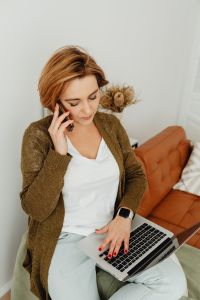 Kaboompics - Remote Work on a Cognac Sofa: Woman on a Phone Call with Laptop