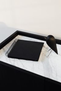 Kaboompics - Black Notebook and Wooden Bird in a Dark Console Tray, Minimalist Interior Detail