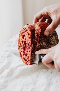 Kaboompics - Vertical Close-Up of Knife Cutting Beetroot Bread