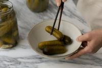 Kaboompics - Hand Serving Pickles in a Ceramic Bowl beside a Glass Jar
